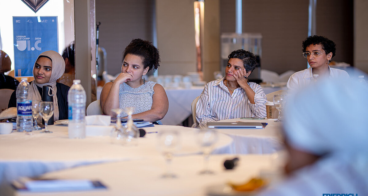 Four women sitting at a table with a critical face expression